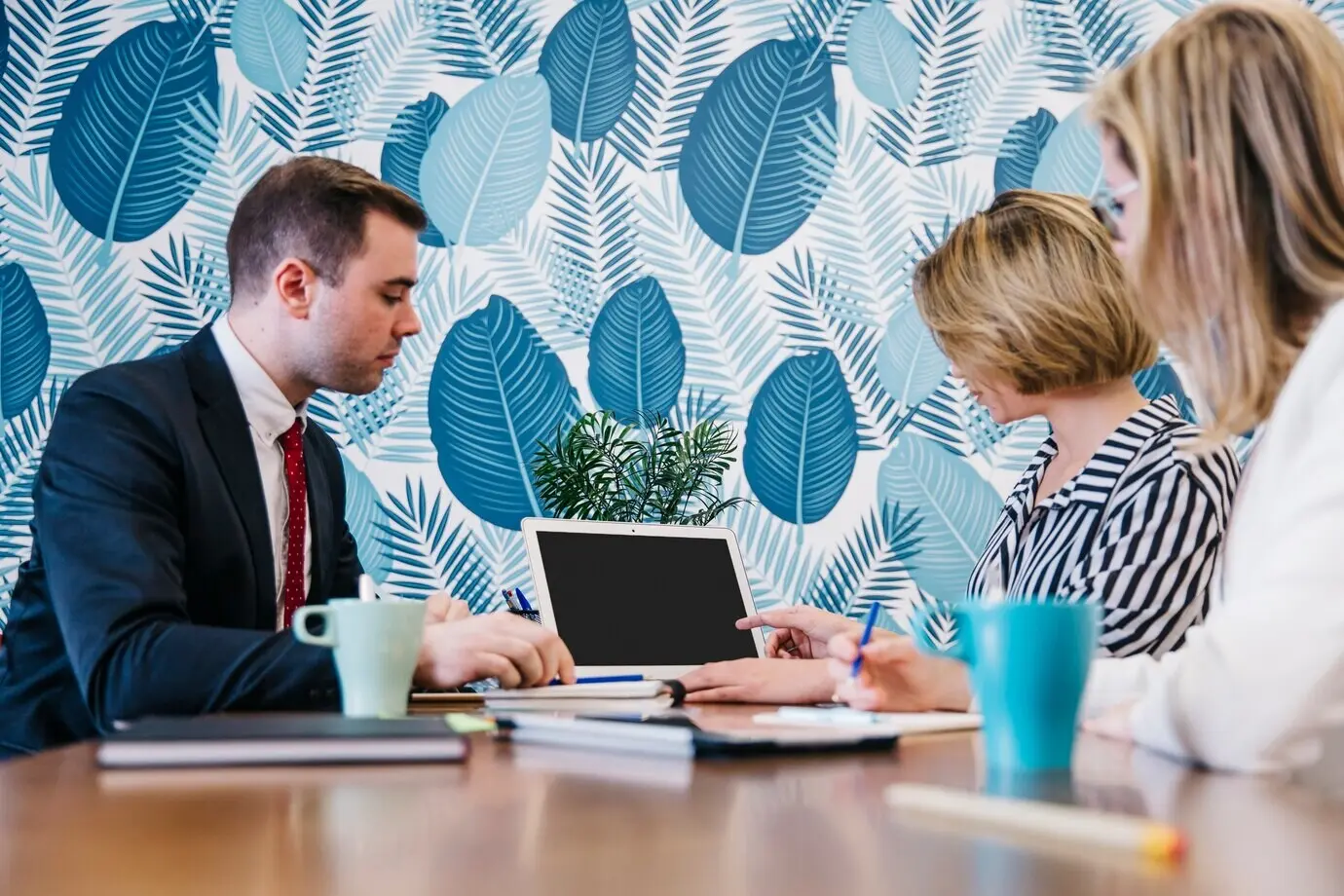 Menschen sitzen und arbeiten gemeinsam an einem Laptop.